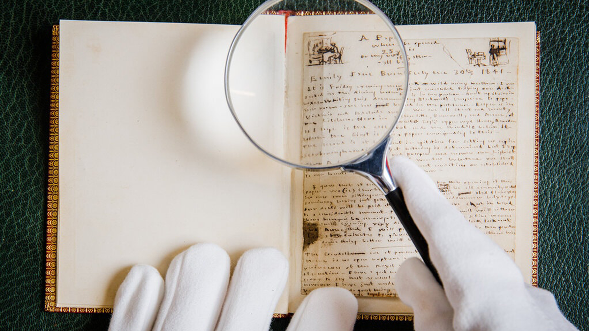 Un employé de musée portant des gants blancs tenant une loupe inspecte un manuscrit ou un livre