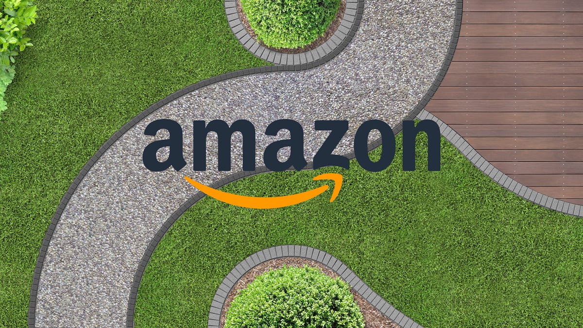 Un logo Amazon au-dessus d'un trottoir serpentant à travers un jardin.