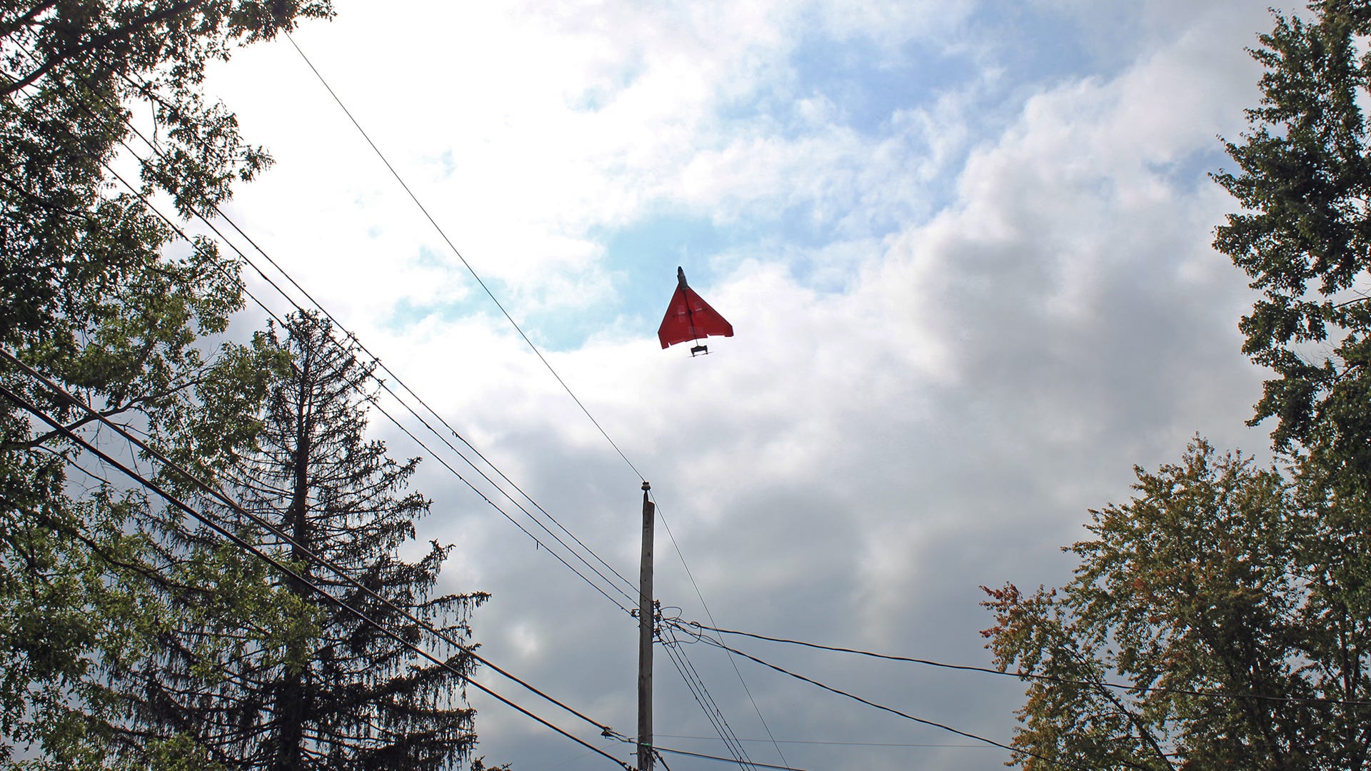 Un avion en papier RC volant haut dans les airs vers les lignes électriques.