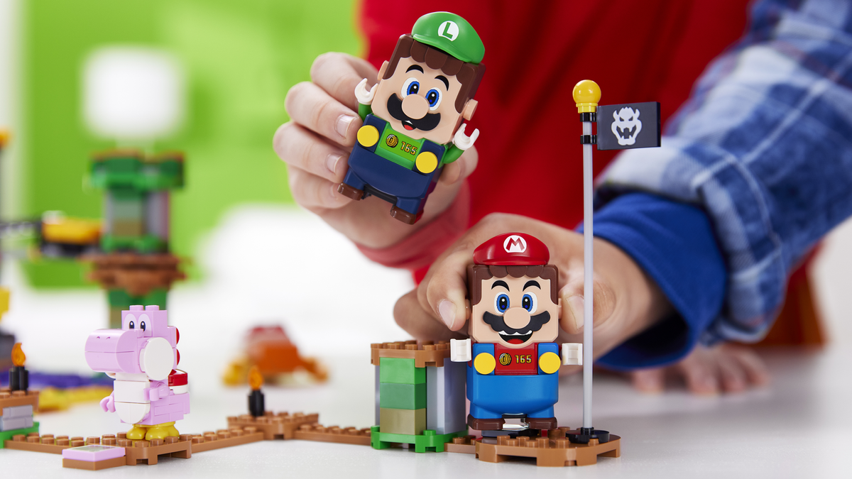 Tangan dua anak memegang Bluetooth LEGO Mario dan LEGO Luigi