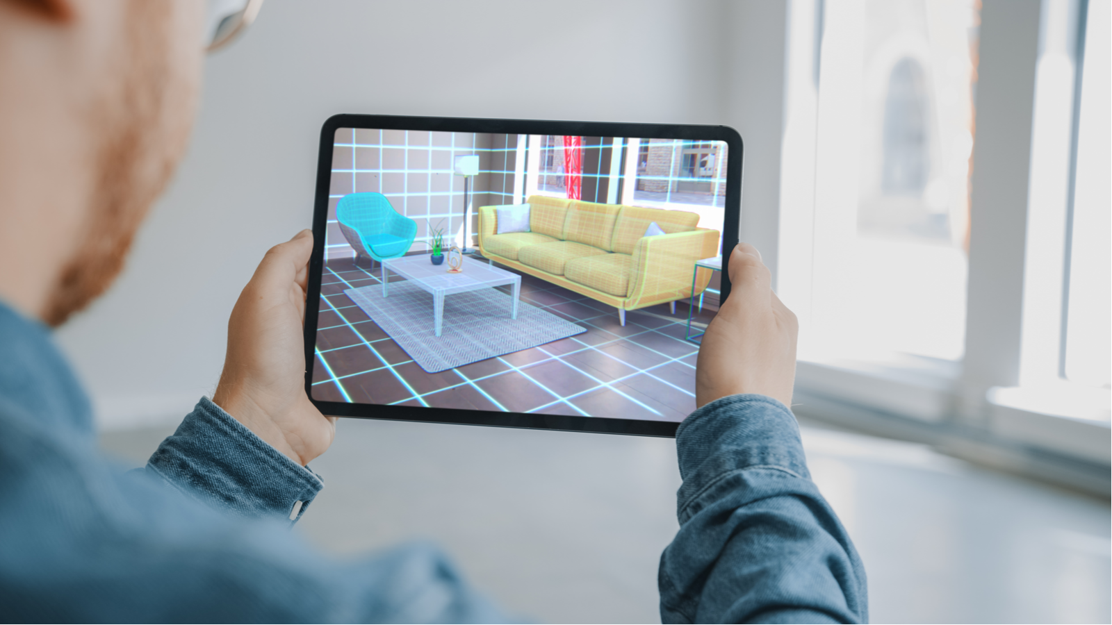 Persoon die een digitale tablet met een augmented reality-app voor interieurontwerp vasthoudt terwijl hij virtueel meubels in de kamer uitprobeert