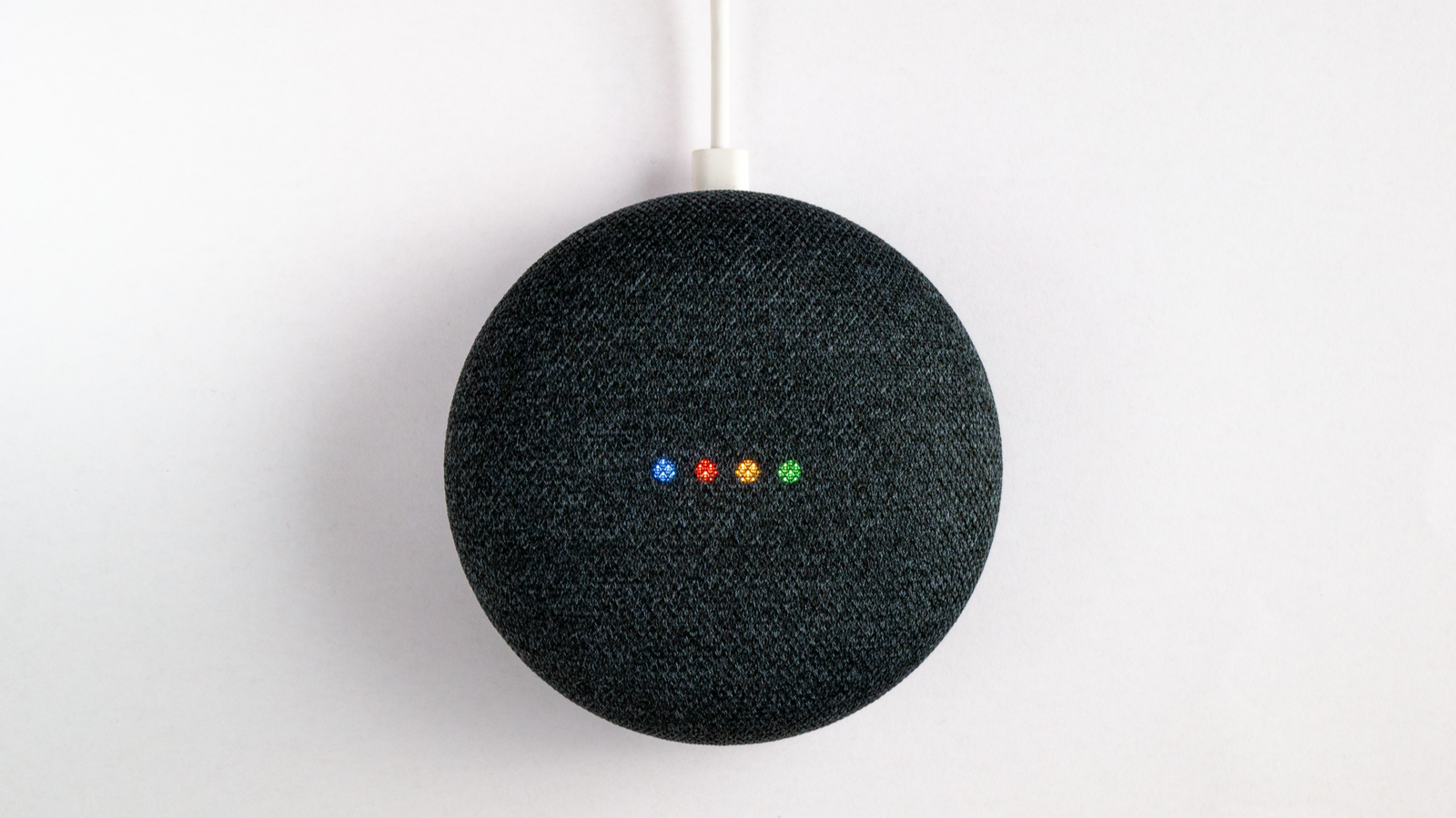 Google Nest mini-speaker spraakgestuurd verlicht op witte achtergrond