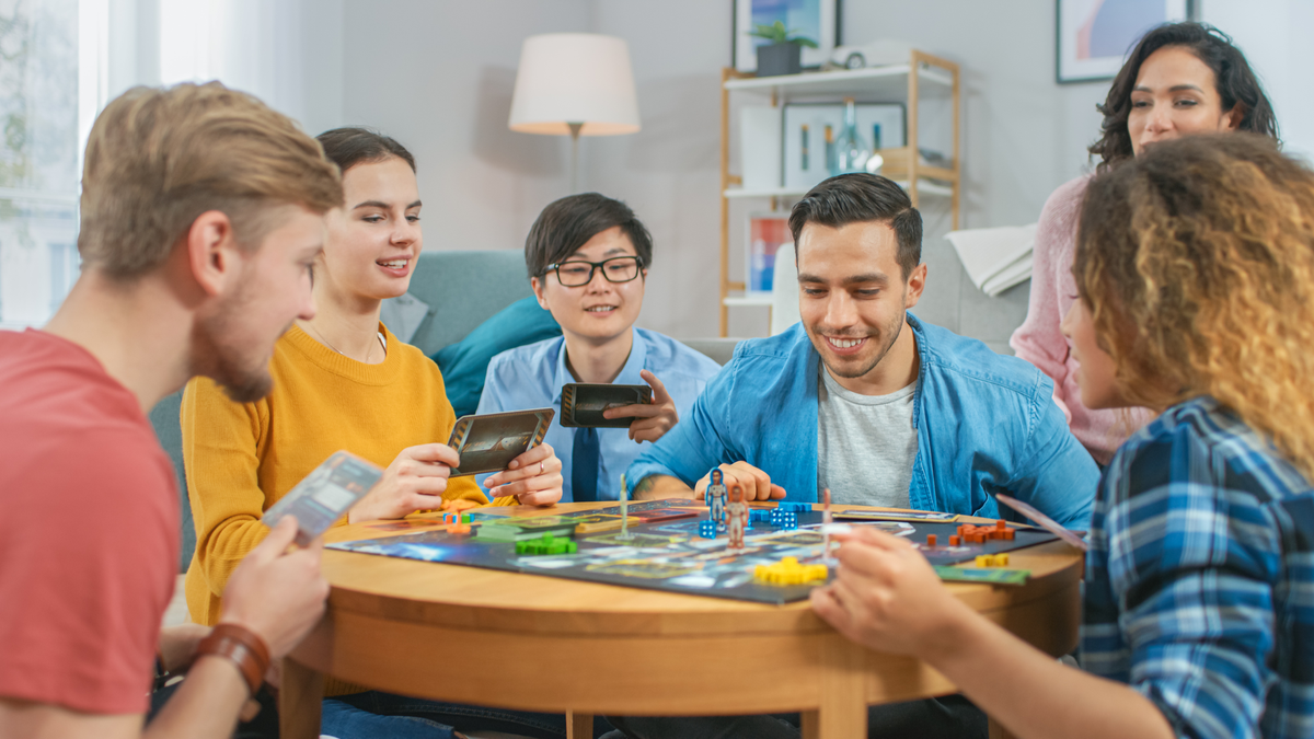 Diverse groep vrienden die rond een tafel een bordspel spelen