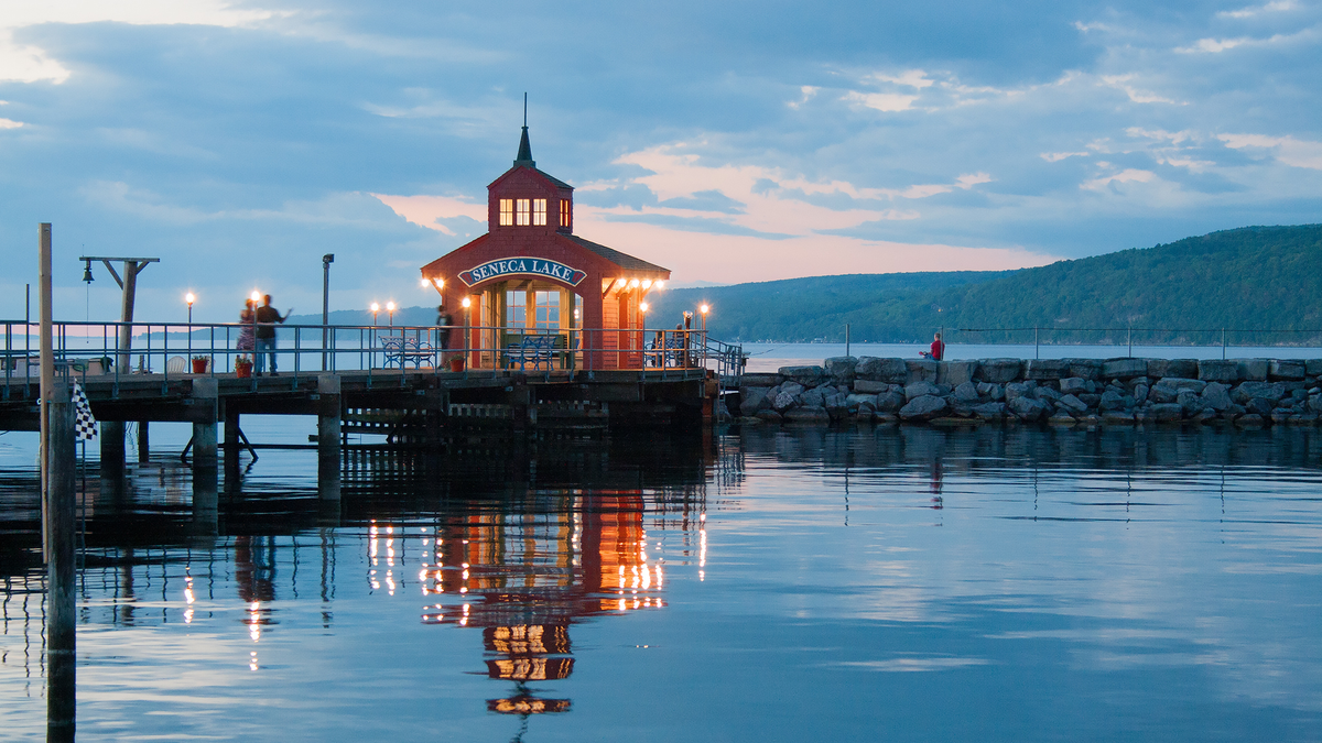 Pier op Seneca Lake met gloeiende lichten bij zonsondergang