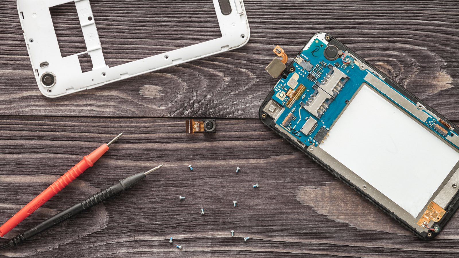 Mobiele telefoon reparatie, opname van de binnenkant van de telefoon naast de buitenbehuizing op houten planken