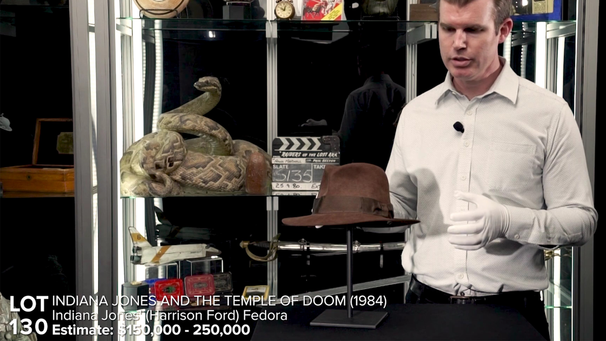 Still van veilinghuisvideo met expert die pronkt met de Indiana Jones-fedora