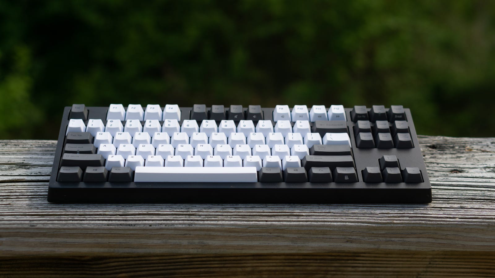 Grijs, tenkeyless mechanisch toetsenbord op een houten reling