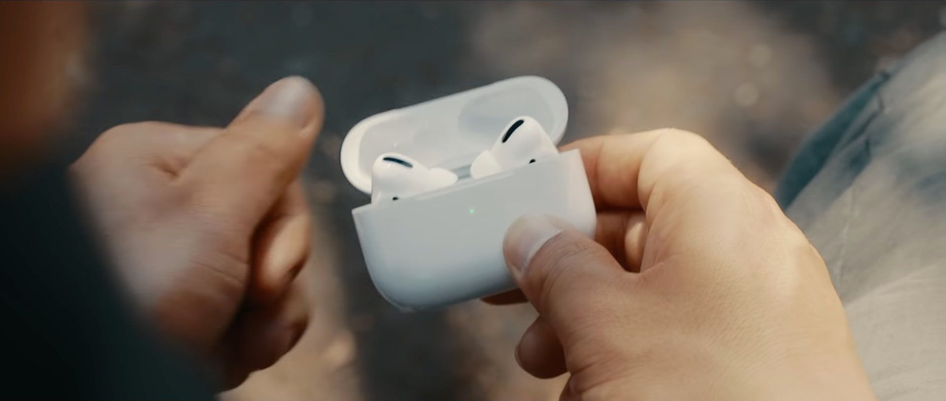 ภาพนิ่งจากโฆษณาของ Apple กำลังแสดงคุณ มือของผู้ชายถือเคสชาร์จ AirPods Pro ที่เปิดอยู่พร้อมหูฟังเอียร์บัดอยู่ข้างใน