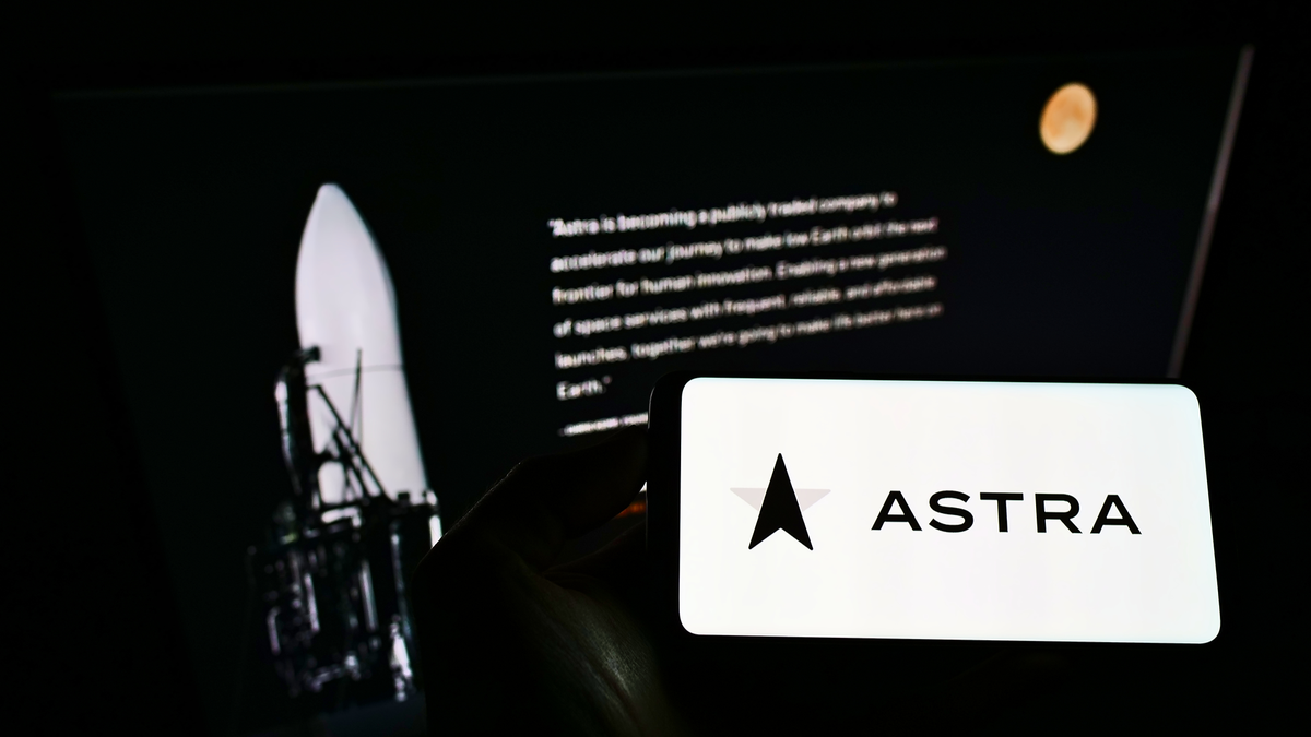 คนถือโทรศัพท์มือถือที่มีโลโก้ของบริษัทการบินและอวกาศอเมริกัน Astra Space Inc. บนหน้าจอด้านหน้าหน้าเว็บ