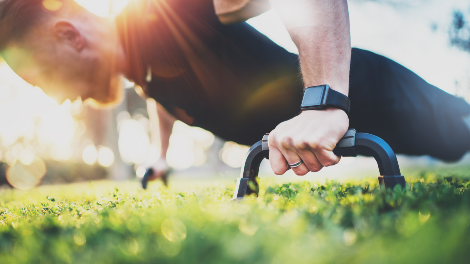 Healthy lifestyle concept with athletic person doing pushups in the park on a sunny morning