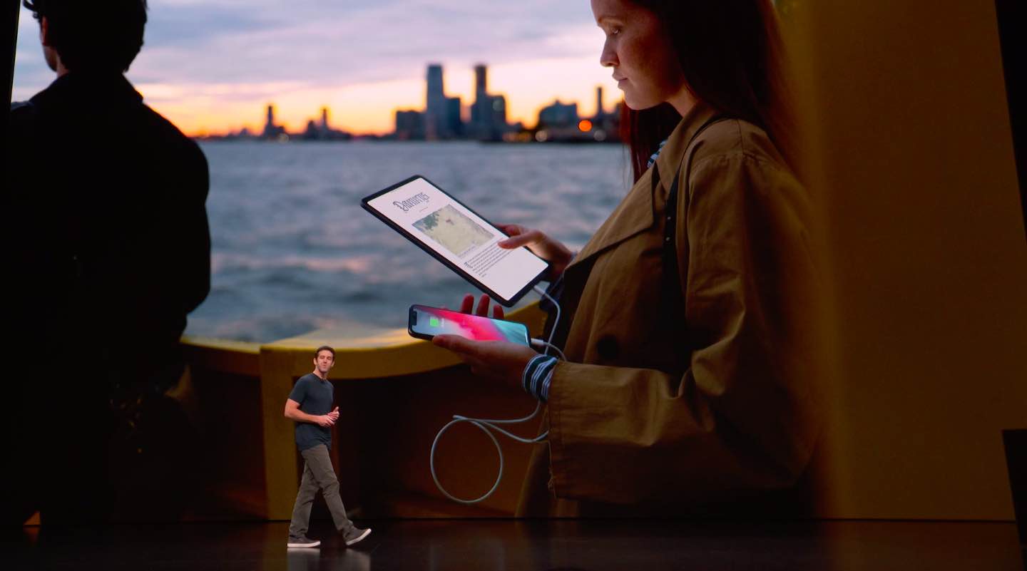 Hình ảnh từ sự kiện năm 2018 của Apple cho thấy một giám đốc điều hành đang đi dạo phía trước một trang trình bày hình ảnh một người phụ nữ cầm iPad Pro và iPhone trên tay được kết nối bằng cáp Lightning to USB-C